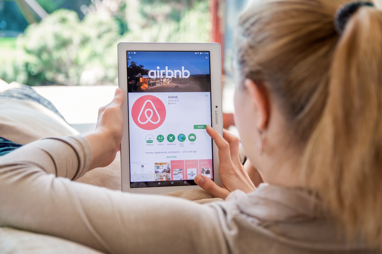 Woman is installing Airbnb application on Lenovo tablet. Airbnb is an online marketplace and hospitality service, enabling people to lease or rent short-term lodging